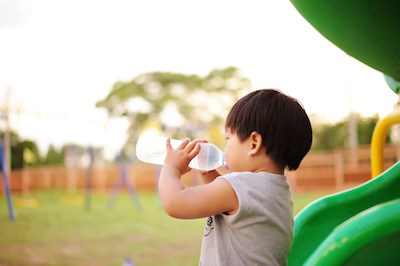 Boy drinking water on playground slide