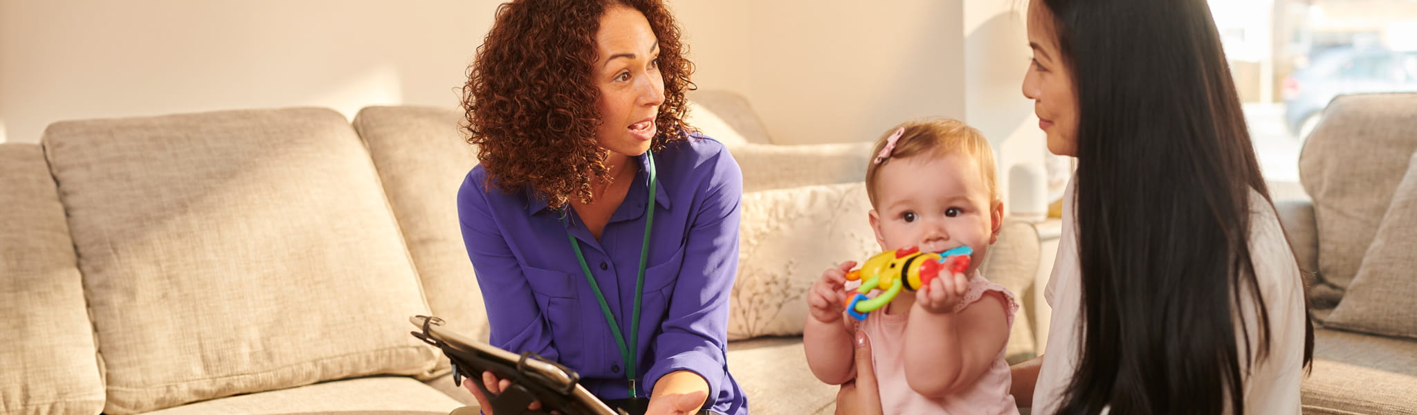 two women talking and a baby sitting in the middle