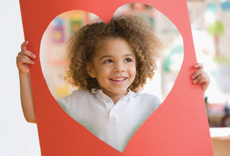 Little Girl standing behind a heart cutout