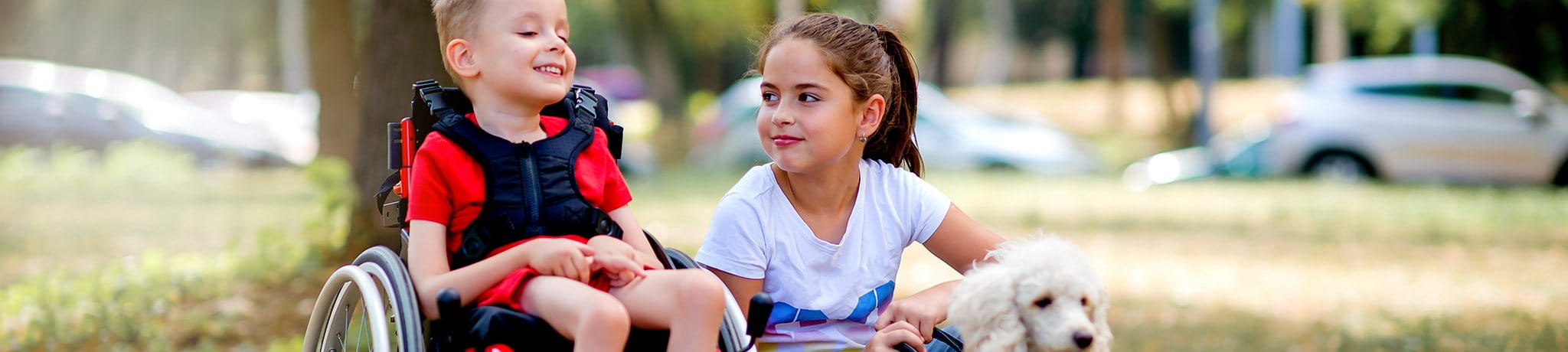 Child in wheelchair with a girl with a dog on leash