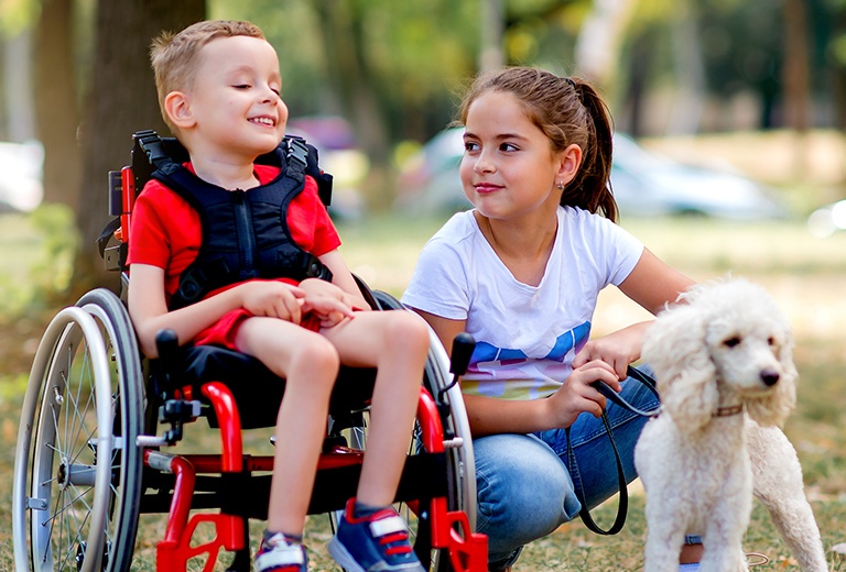 Child in wheelchair with a girl with a dog on leash