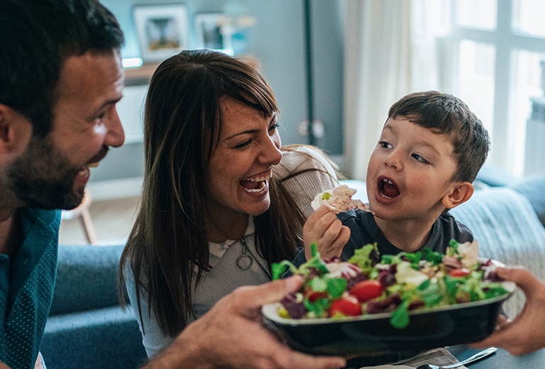 Mom and Dad feeding child with salad