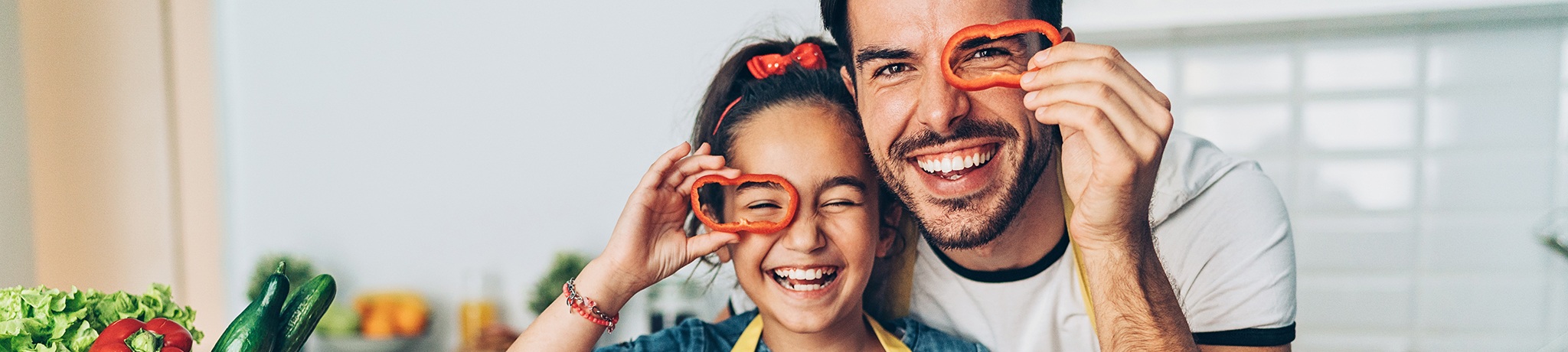 Father and daughter holding red pepper rings over their eyes