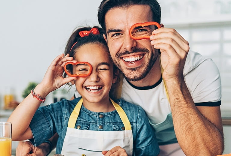 Father and daughter holding red pepper rings over their eyes