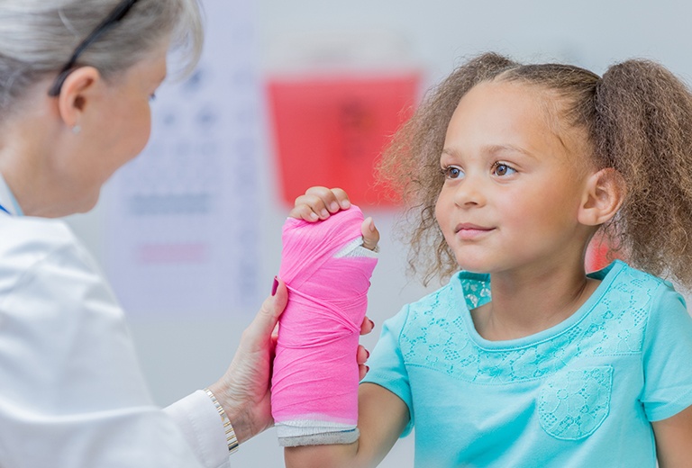 Girl with pink cast with doctor