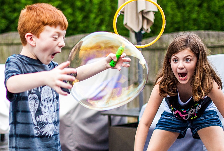 Two kids playing with large bubble