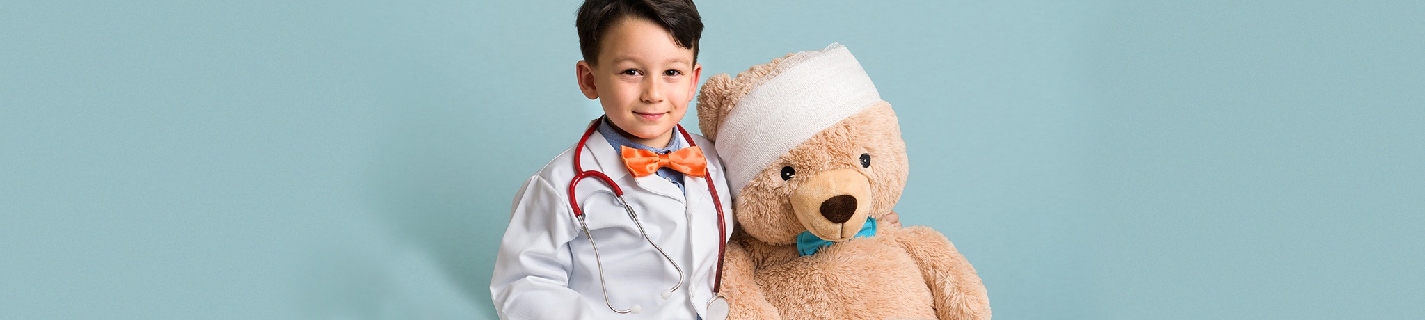 Boy dressed as doctor with teddy bear with wrap around head