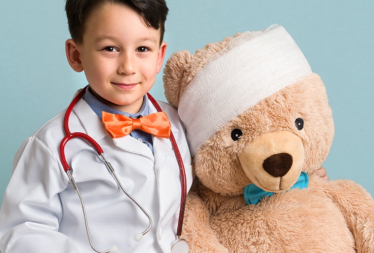 Boy dressed as doctor with teddy bear with wrap around head