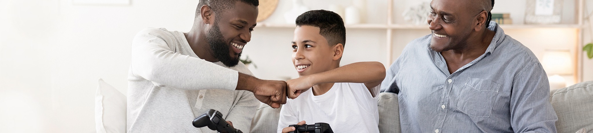 Two men and a boy playing video games bumping fists