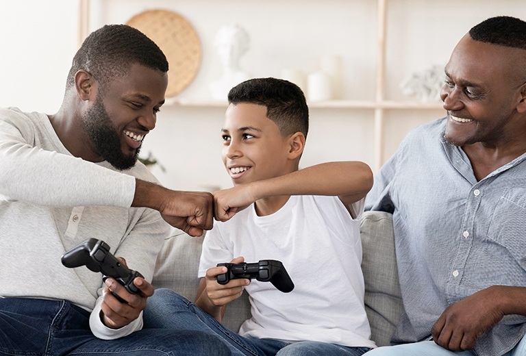 Two men and a boy playing video games bumping fists