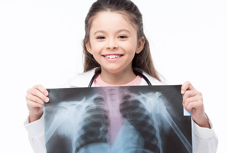 Girl dressed as doctor holding image of x-ray