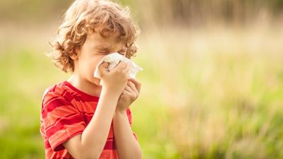 Boy blowing nose outside