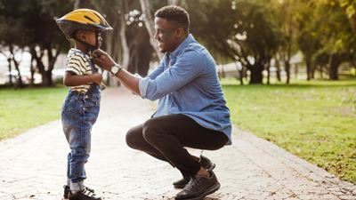 Father putting helmet on son