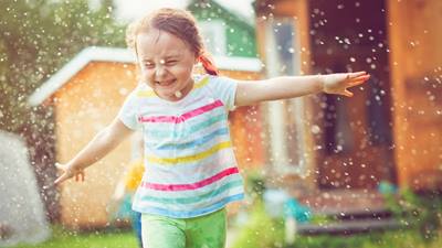 Little girl plays in sprinkler