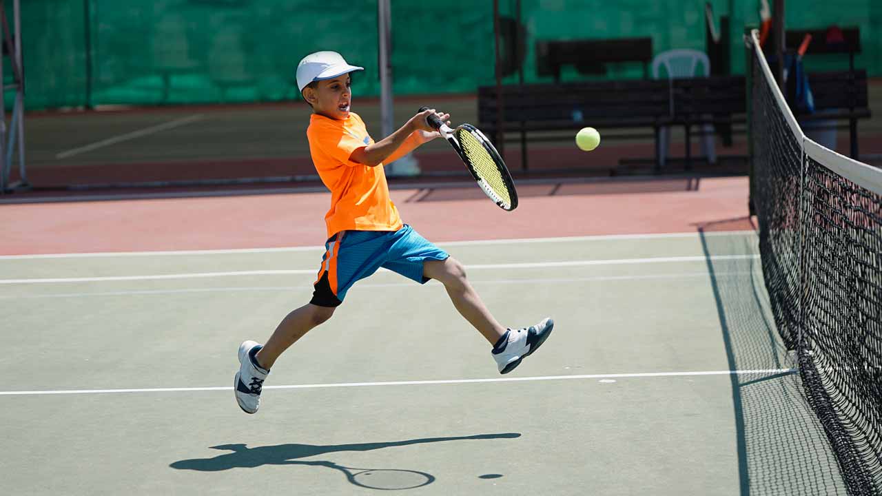 Young boy swinging tennis racket