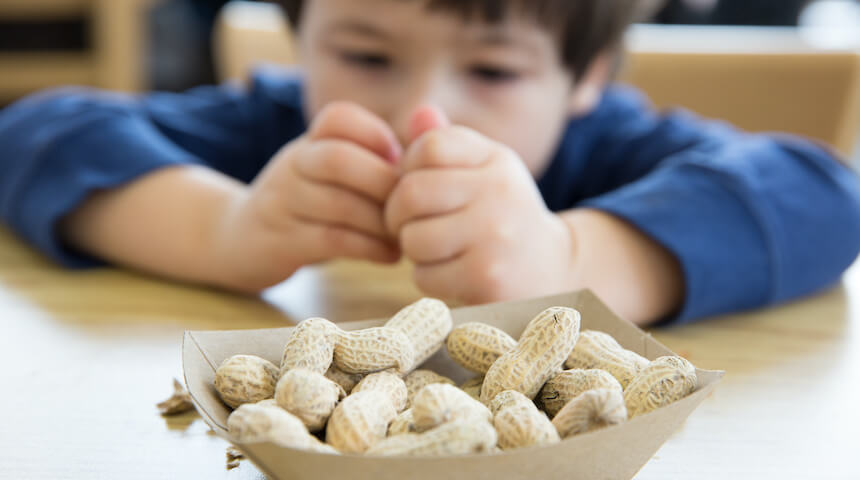 Toddler sitting in front of a bowl of peanuts