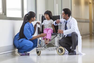 Child in wheelchair talking to hospital staff