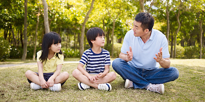 Father speaking to children in a park