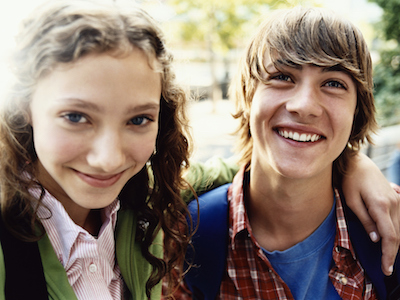 Teenage Girl Stands Smiling With Her Arm Around Her Friend