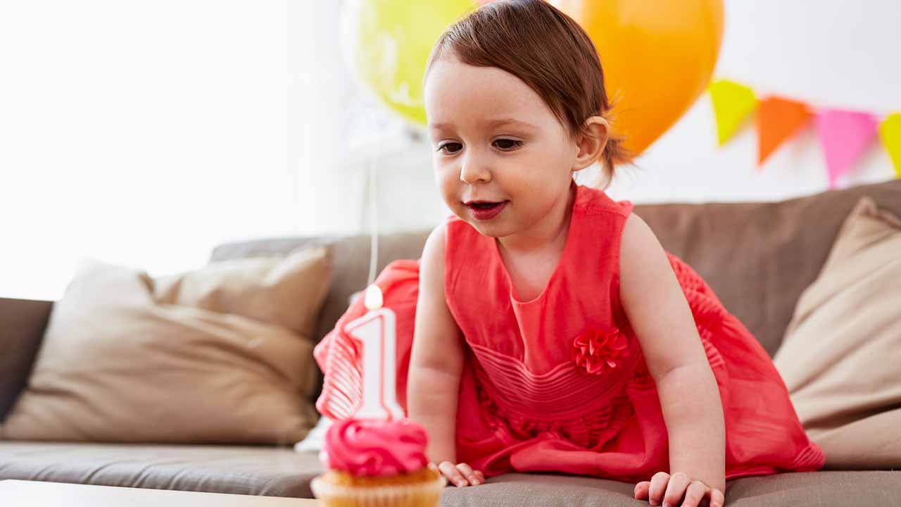 Baby blowing out a birthday candle on cupcake