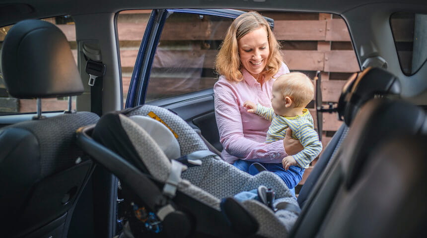 Mother putting baby in a car seat