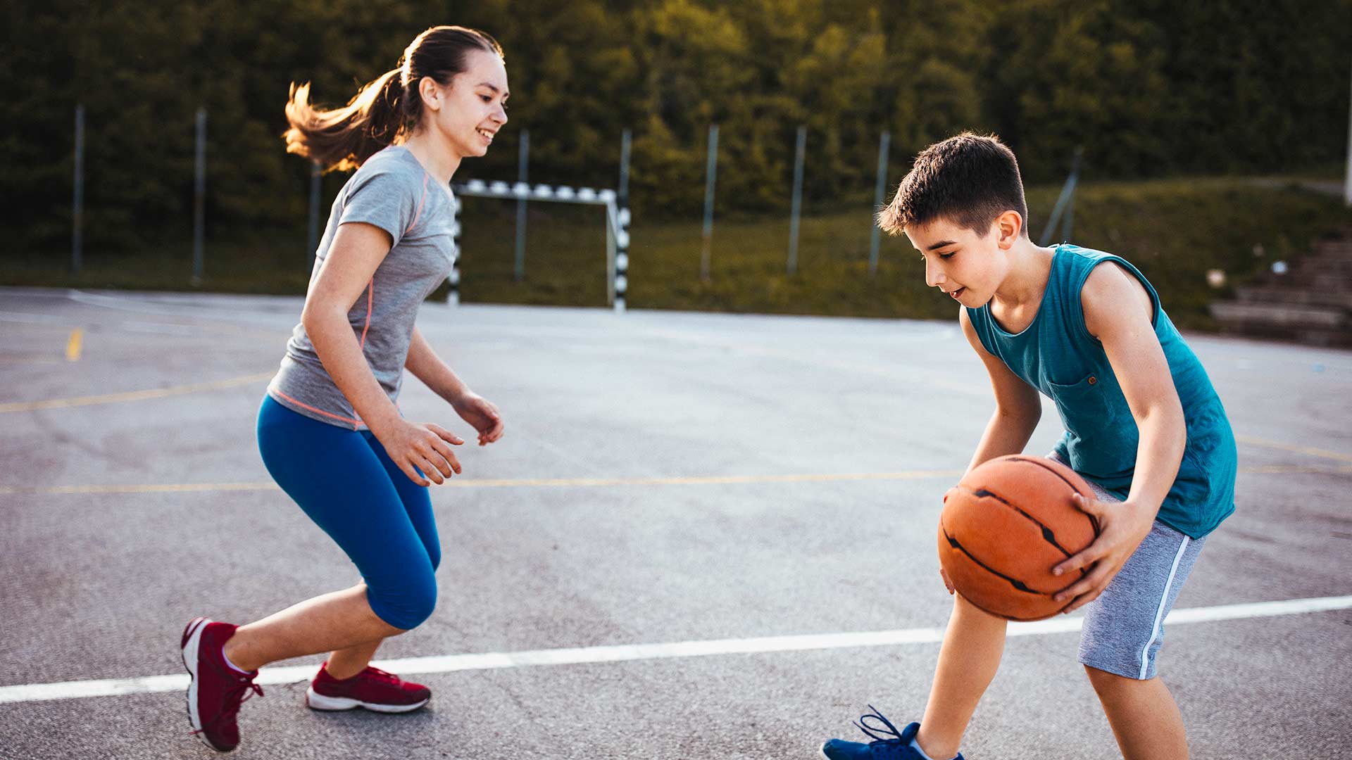 Sister and brother playing basketball outdoors